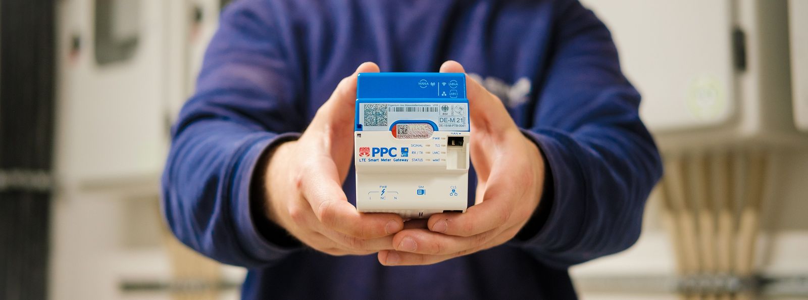 Person hält einen modernen Smart Meter Zähler mit blau-weißem Gehäuse in beiden Händen