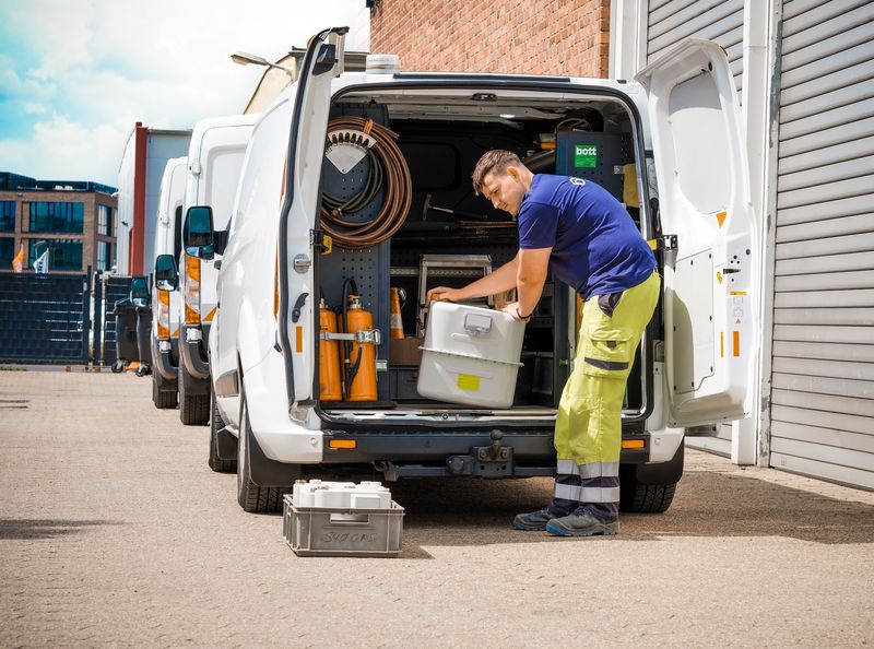 Mitarbeiter in Sicherheitskleidung lädt technische Ausrüstung aus einem weißen Transporter