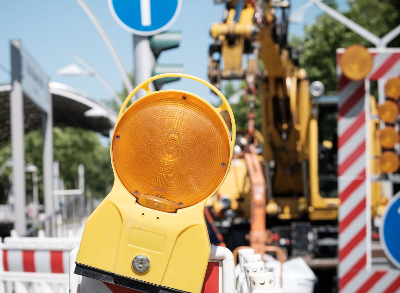 Auf dem Bild ist eine Baustellenampel und ein Baukran im Hintergrund zu sehen