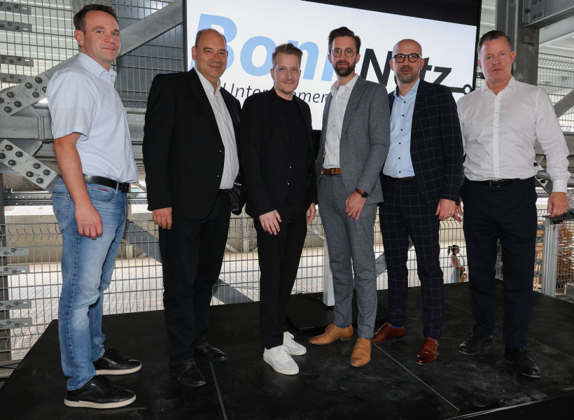 Auf einer Bühne stehen in einer Reihe sechs Männer, die der aktuellen bzw. zukünftigen Geschäftsführung von BonnNetz, den SWB oder dem Betriebsrat angehören.